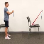 Person performing standing hamstring curls with resistance band for knee injury recovery exercises step by step